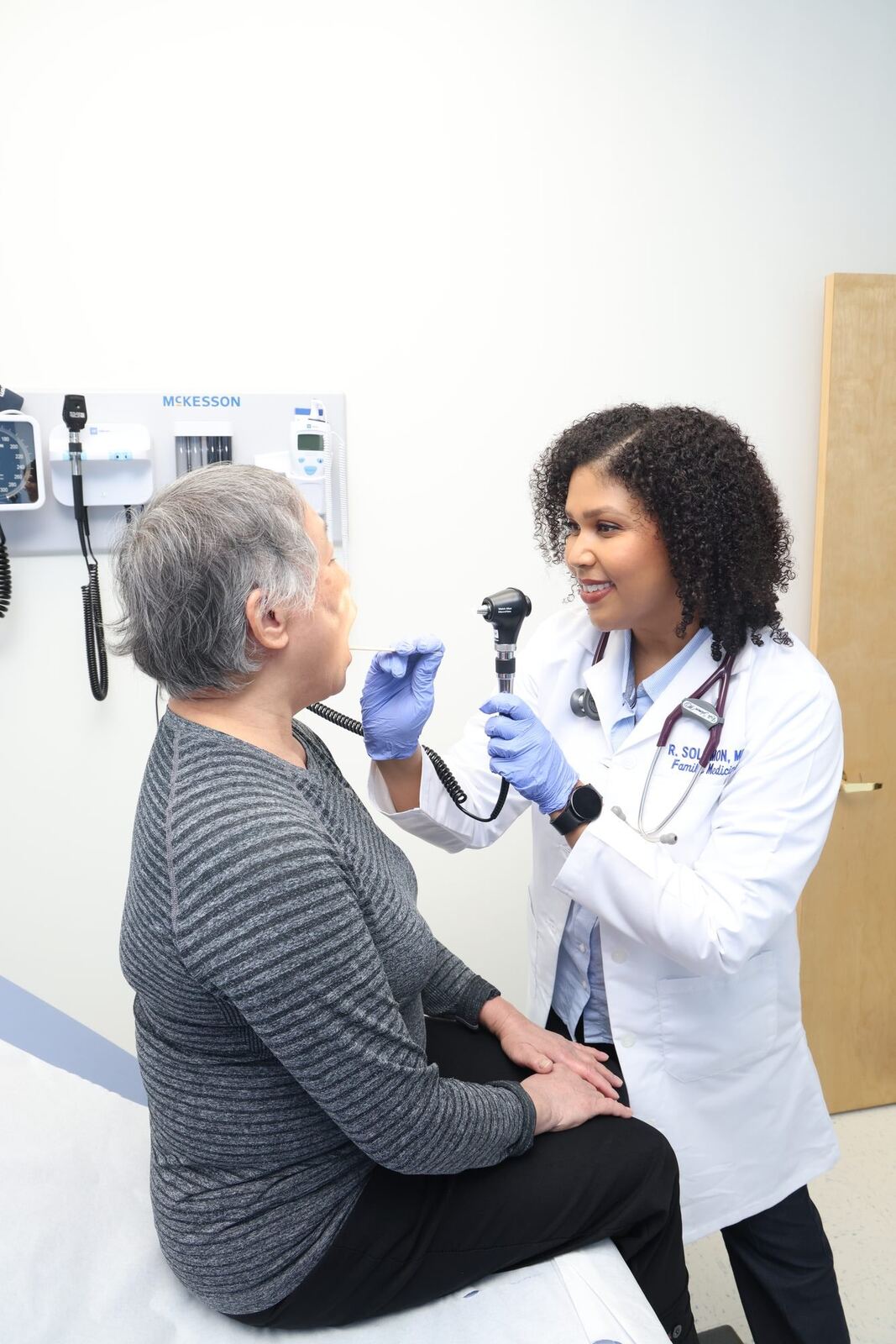Dr. Ruth Solomon looking at an elderly woman with grey hair during an exam